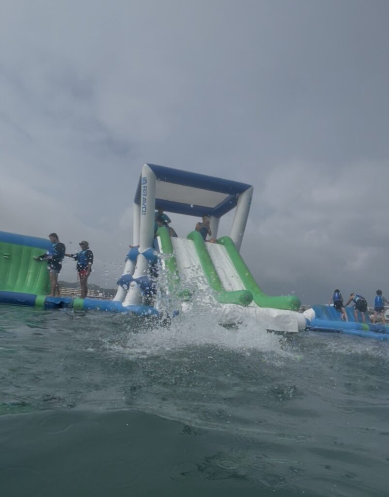 逗子海岸ウォーターパークを海上から見た様子。青と白の大型海上アスレチックの滑り台。