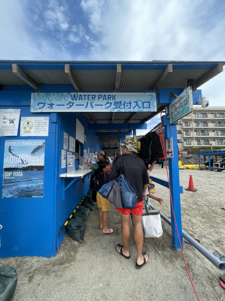 逗子ウォーターパークの受付入口。青い小屋の中でスタッフが来場者を案内している。