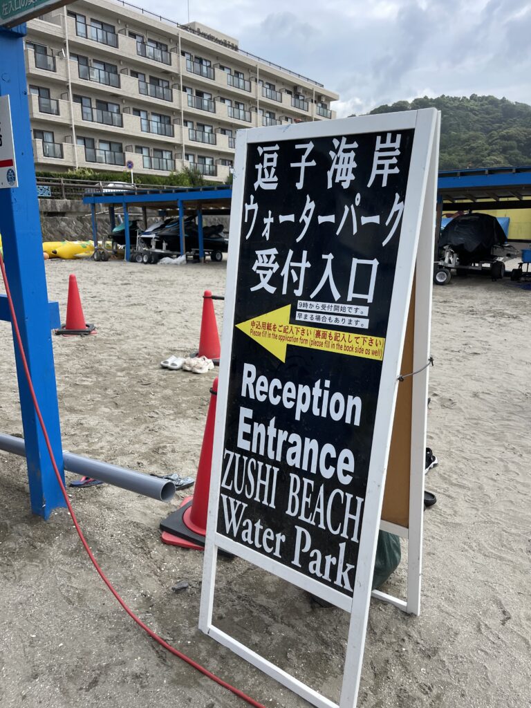 逗子ウォーターパークの入口受付パネル。黄色と黒の看板に英語と日本語で「Reception Entrance」と書かれている。